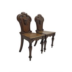 Pair Victorian oak hall chairs, scallop shaped back with carved scrolls and central shield moulding, panel seat over shaped frieze rail, raised on turned supports