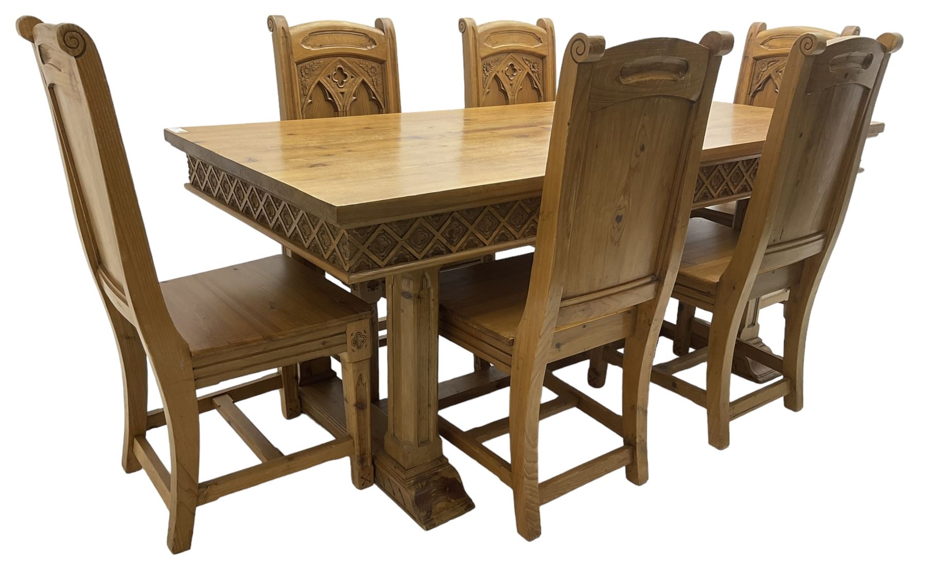 Ecclesiastical Gothic design waxed pine dining table, rectangular top over frieze carved with lattice pattern, raised on square chamfered supports with tracery style carving, on sledge feet joined by stretcher (W185cm D90cm H77cm); and set six matching chairs, high panelled back with carved and moulded gothic tracery window decoration and flower heads, panel seat over carved frieze rail and square tapering supports (W48cm H104cm)