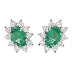 Pair of 18ct white gold emerald and diamond earrings, each stud set with a single oval cut emerald, surrounded by ten round brilliant cut diamonds, stamped, total emerald weight approx 0.90 carat, total diamond weight approx 0.55 carat
