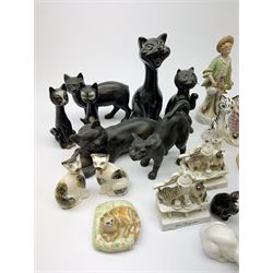 A collection of various ceramic figurines, to include pair of small 19th century Staffordshire cats, Royal Doulton cat, Coalport cat, pair of 19th century pug dogs, two fairings inscribed Good Templars, two Bonzo dog peppers, a number of pin cushion dolls, various 20th century and later black pottery cats, Victorian bisque figures, etc. 
