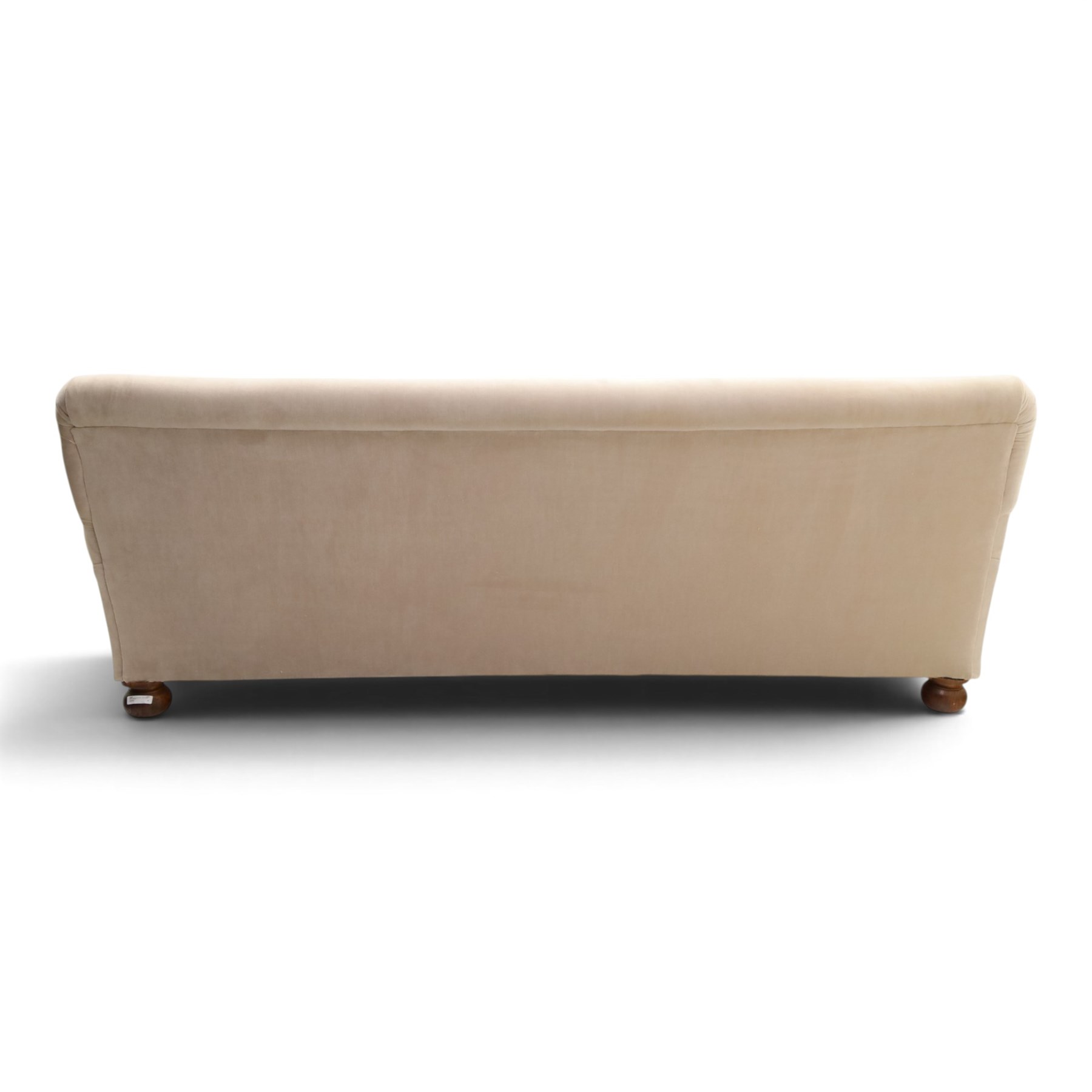Late Victorian oak framed low three-seat settee, of traditional shape with low rolled sprung back over rolled arms and sprung seat, raised on front turned feet, upholstered in beige fabric