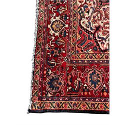 Persian Hamadan indigo and red ground carpet, large central medallion decorated with projecting palmette motifs, the surrounding field decorated with trailing branches and flower heads, crimson ground border decorated with stylised plant motifs, within floral pattern guard stripes 