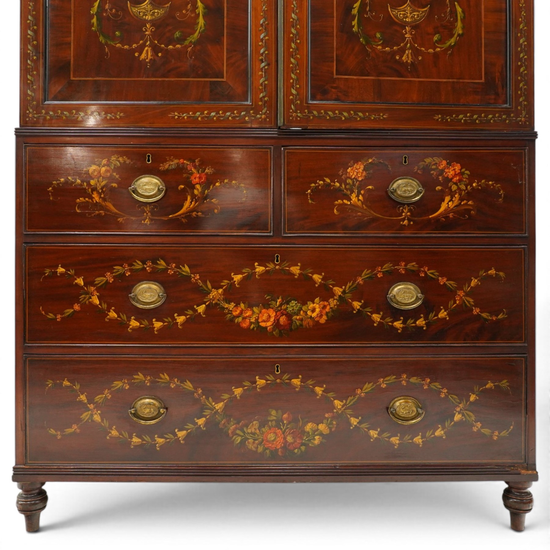 19th century French Louis XVI design mahogany and polychrome painted gentleman's press wardrobe - projecting cavetto cornice with urn and bellflower painted frieze, the twin doors with classical figural medallions surmounted by urns and festoon decoration with scrolling acanthus leaves, enclosing five sliding trays, the base fitted with two short over three long cock-beaded drawers, the facias painted with interlocking swags and garlands of bouquets with recumbent lion brass handle-plates, lower reeded edge on turned feet