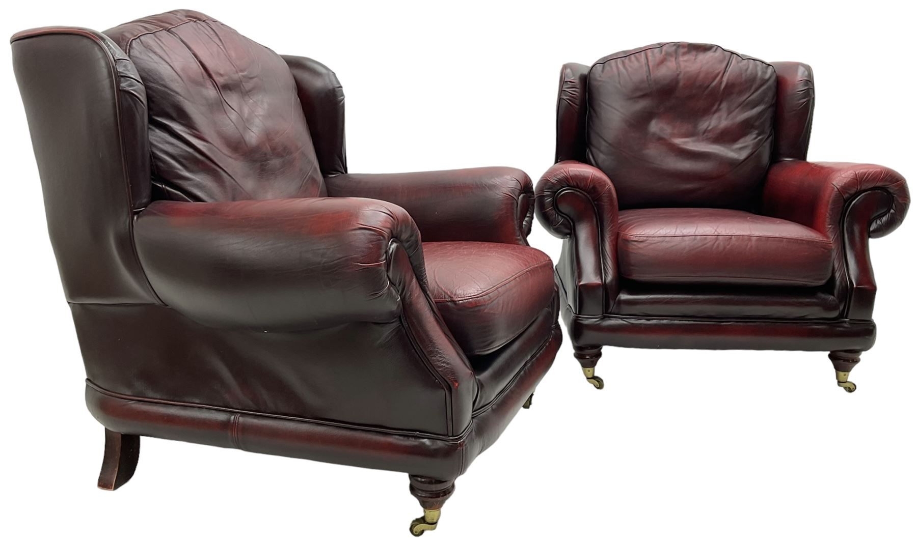 Thomas Lloyd - three-piece lounge suite, comprising of traditional shape two seat sofa (W190cm H80cm) and a pair of wingback armchairs (W100cm H91cm), each with rolled arms over turned supports with brass castors, upholstered in oxblood red leather
