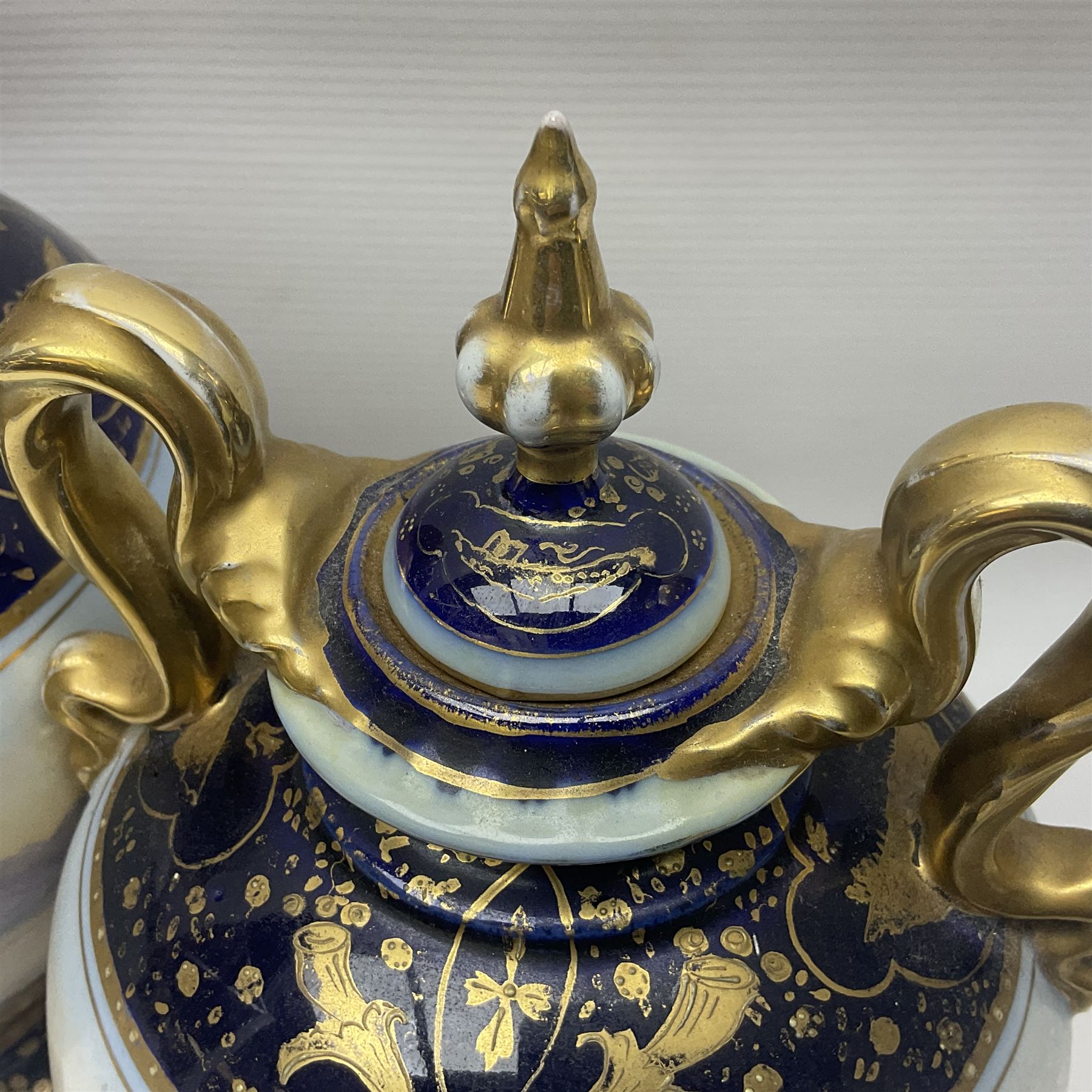 19th century Vienna style porcelain 'Musik' garniture, the central vase of baluster form with domed cover flanked by two smaller vases with twin curved gilt handles to short neck, each decorated with classical figural vignettes between blue borders heightened with gilt, H33.5cm