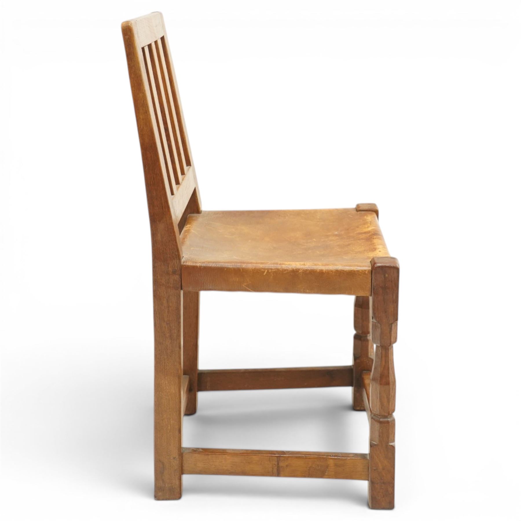 Mouseman - 1940s oak side chair, the slat-back over a slung leather seat, raised on octagonal front supports united by box stretcher, carved with slim mouse signature, by the workshop of Robert Thompson of Kilburn