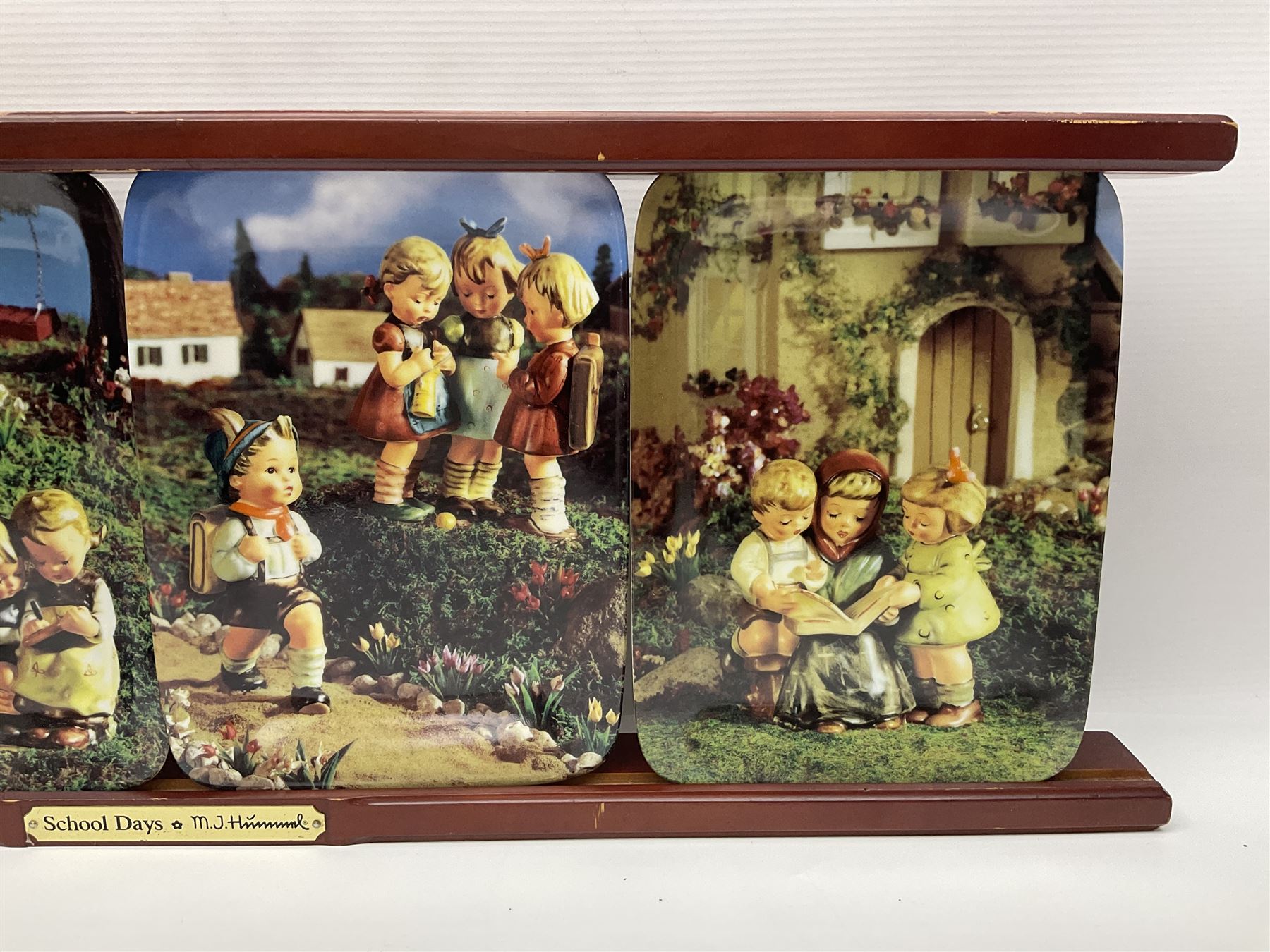 Two ceramic Hummel postcards by Goebel, both displayed on wooden easels, together nine Hummel eggs, set of four Hummel School Days plates, on wooden hanging rack, Goebel Collectors Club Member plaque etc