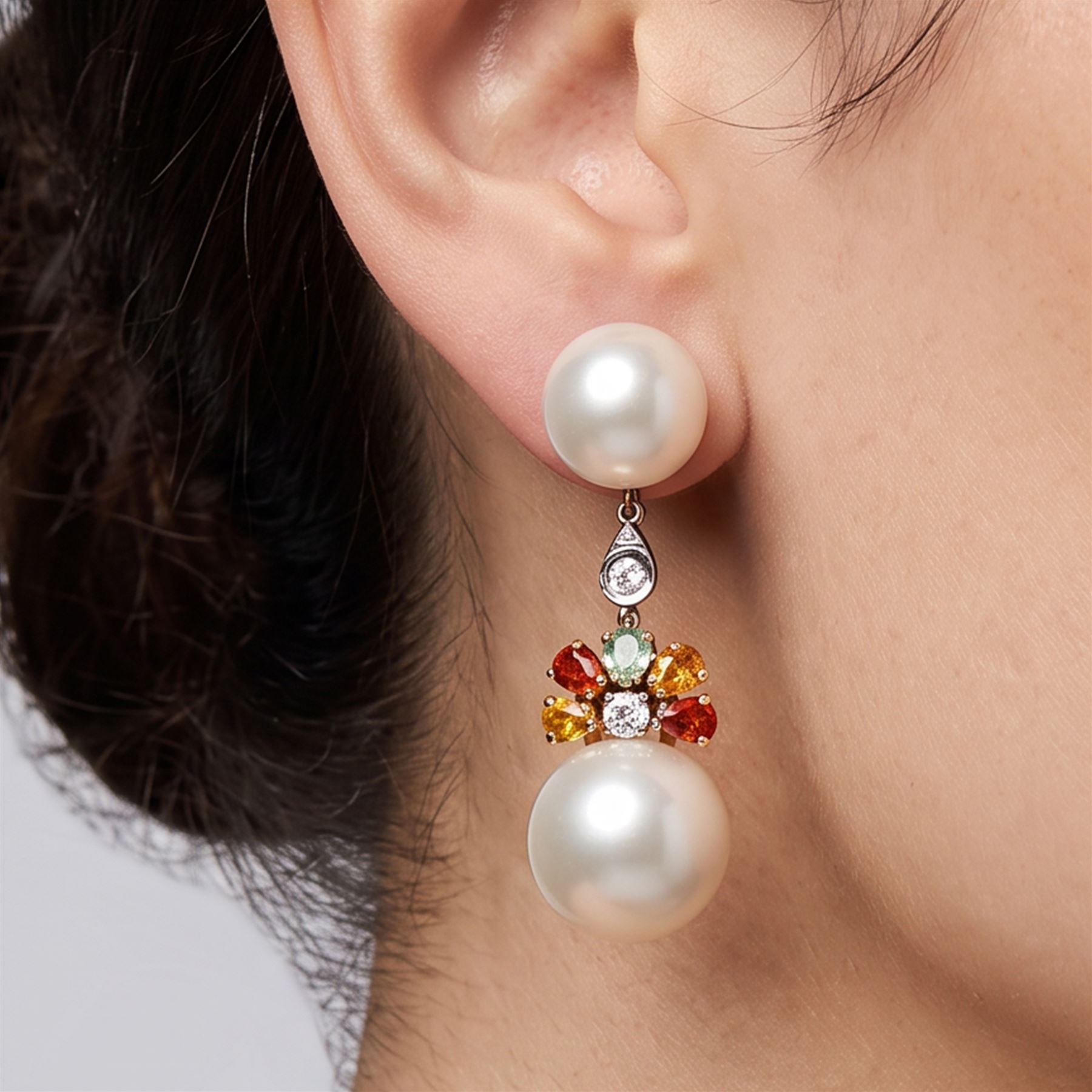 Pair of 14ct white and yellow gold South Sea pearl, diamond and sapphire pendant earrings, each stud set with two pearls, spaced by a single round brilliant cut diamond, suspending a further diamond surrounded by five pear cut yellow, orange and green sapphires, stamped 585