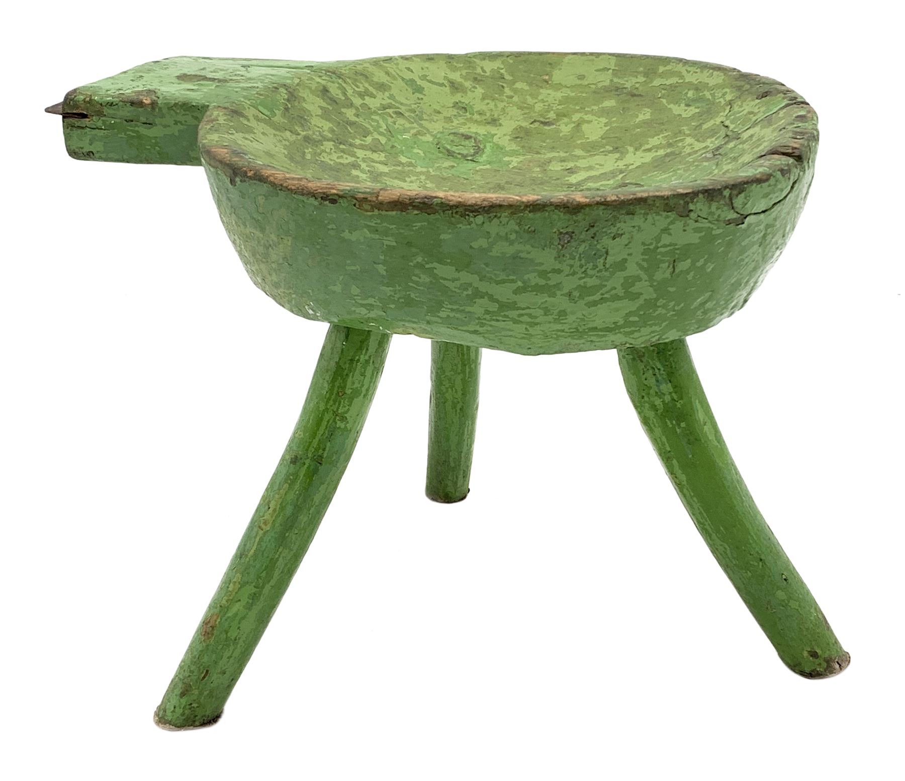 18th/19th century vernacular primitive green painted stool with dished seat fitted with metal scraper to one end, on three splayed legs, L46cm, H34cm