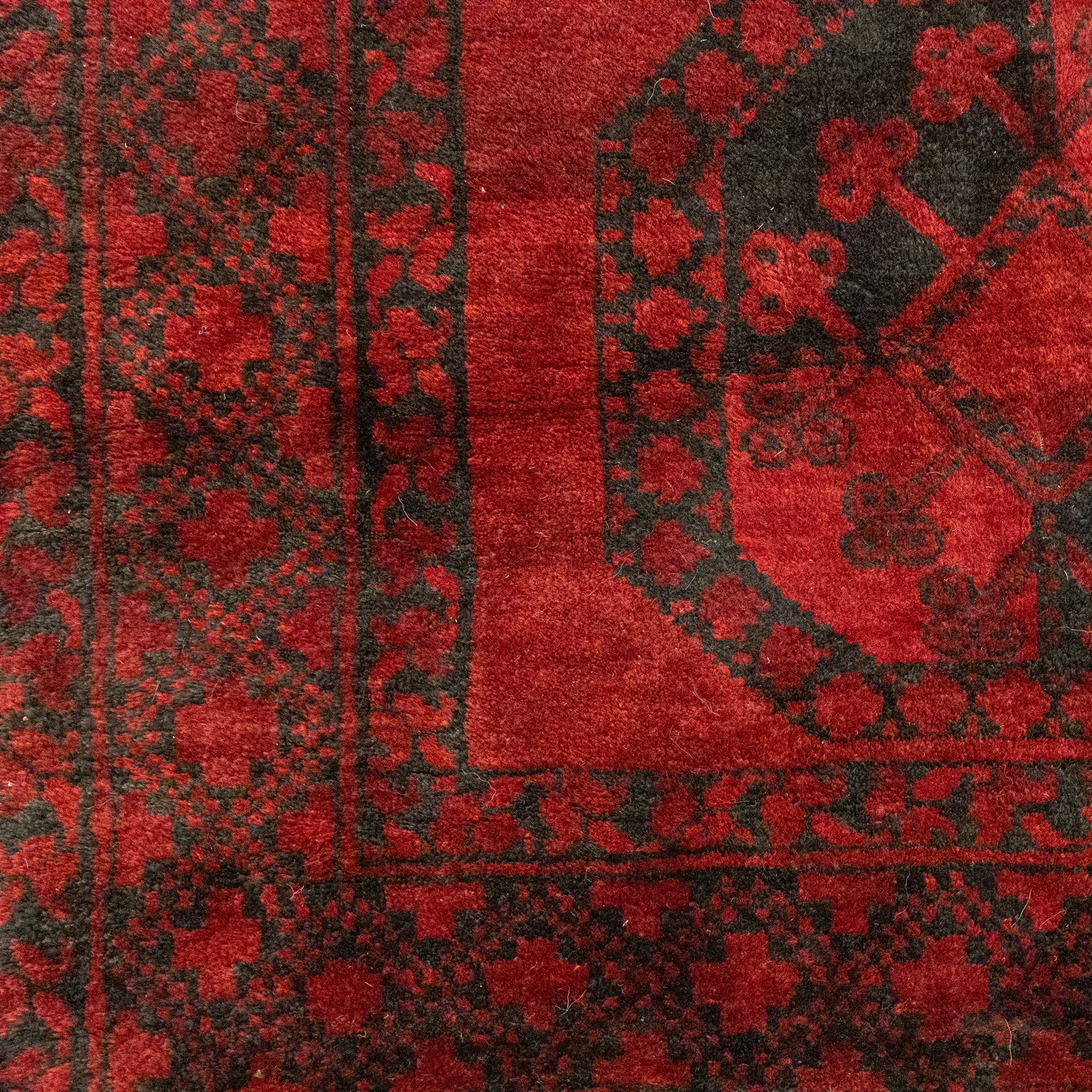 Turkmen Bokhara carpet, with a deep red field and repeating rows of black gul motifs, within multiple geometric borders