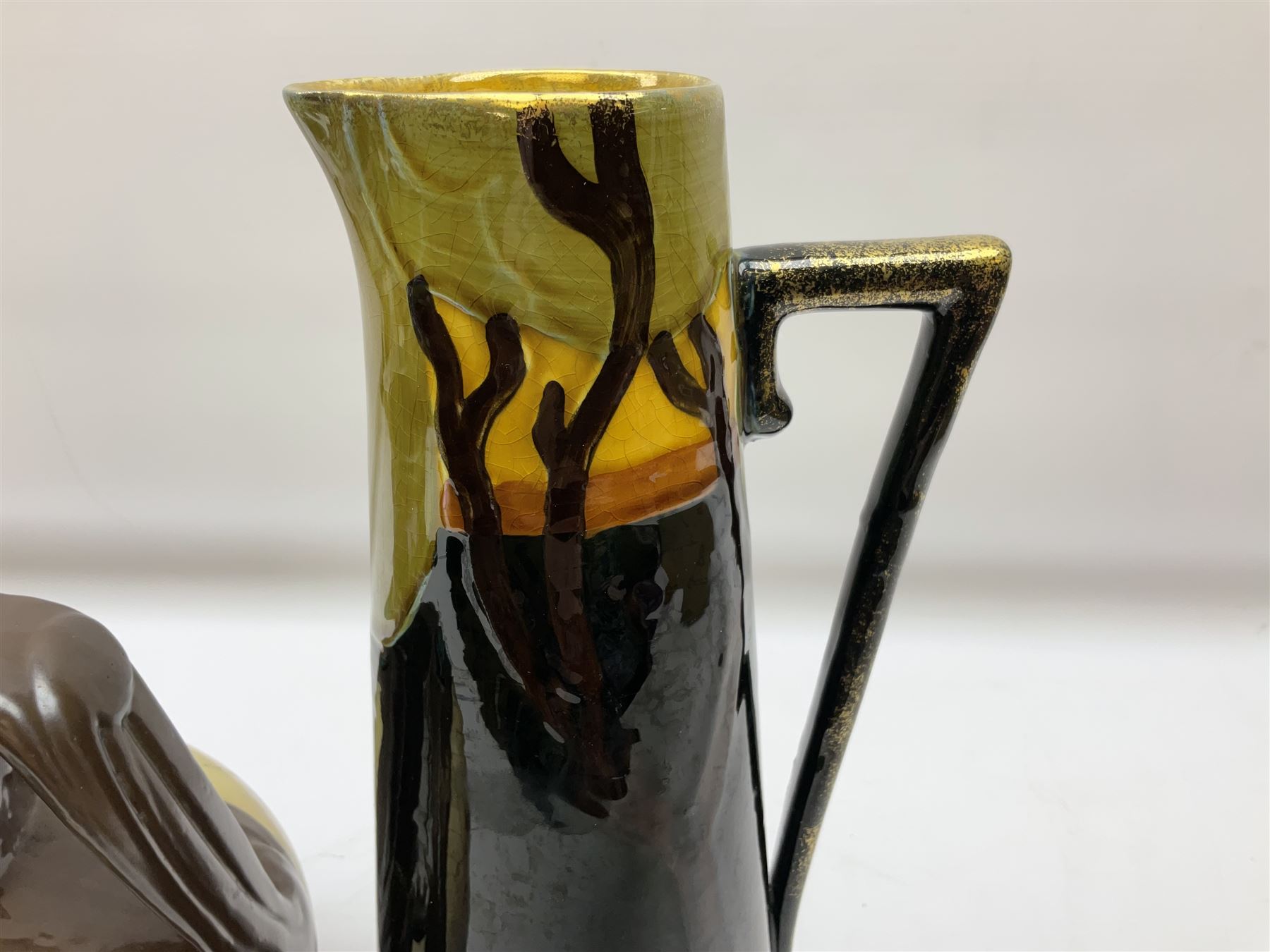 T. Forester Phoenix ware ewer of tapering form decorated with peacock and Bretby twin handled vase decorated with figures fishing in a boat sea scene