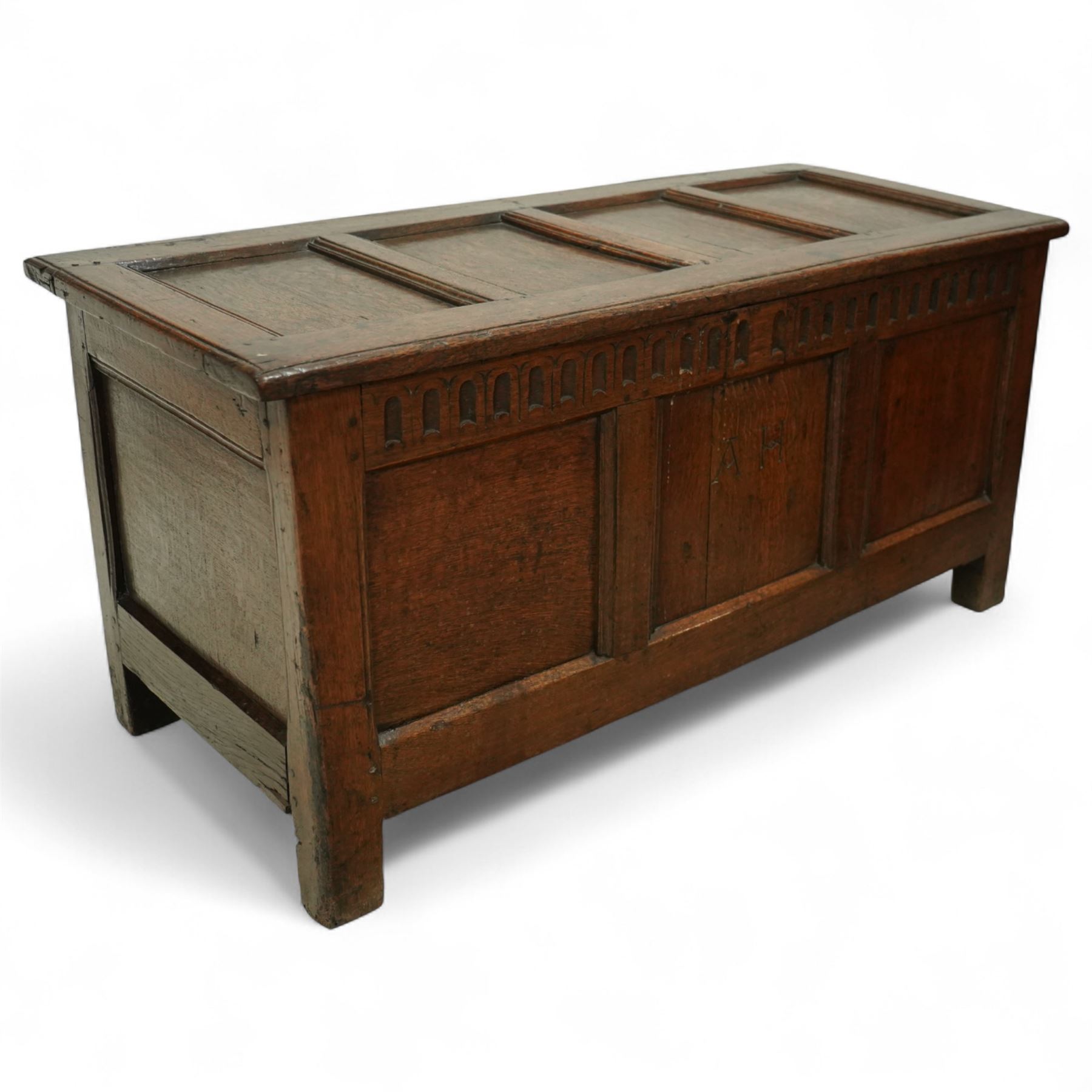 18th century and later oak coffer, the hinged plank top above a panelled front carved with lunette frieze, plain stiles and rails, carved with initials ‘AH’, pegged construction throughout