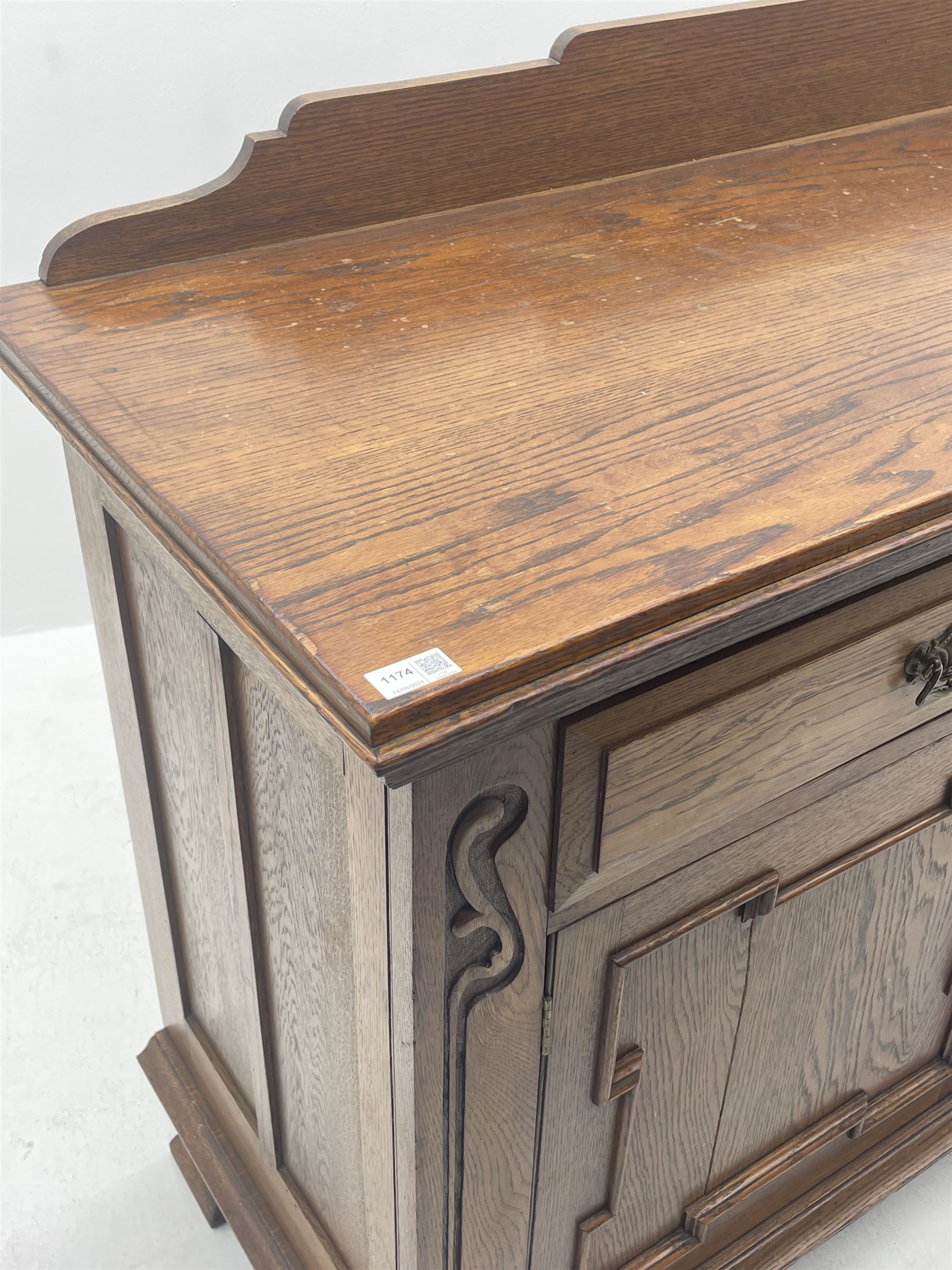 Edwardian oak sideboard, raised and shaped back, two short drawers above two cupboard doors enclosing fitted interior, shaped bracket supports