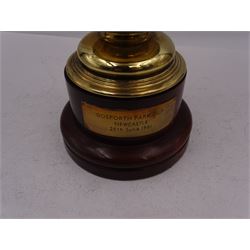 Edwardian silver-gilt twin handled trophy cup and cover, with two curved handles, the domed cover with urn finial, upon domed stepped foot and cylindrical mahogany base with applied plaque, hallmarked Skinner & Co, London 1908, total H29.7cm