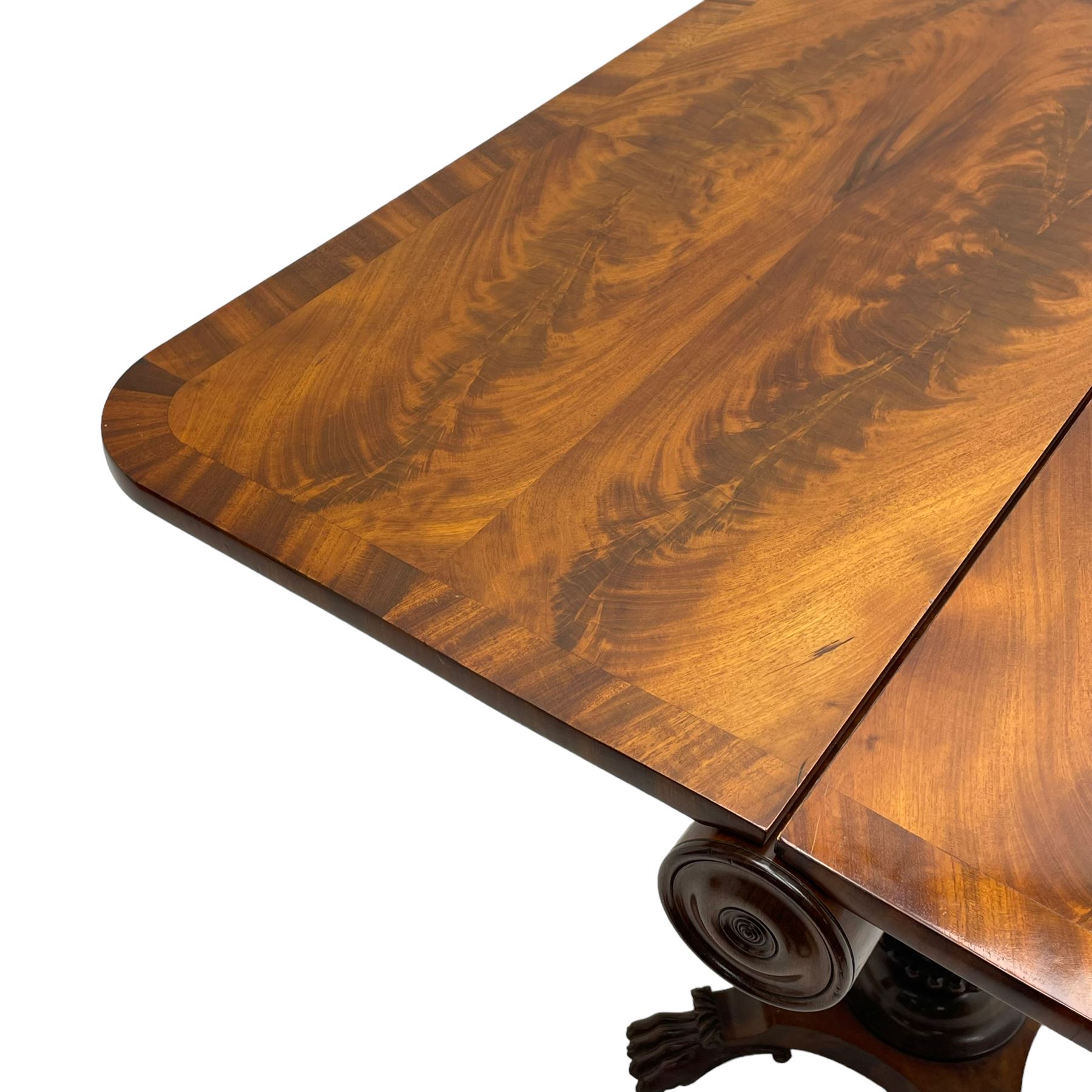 Unusual William IV mahogany Sutherland table, figured and book-matched rectangular drop-leaf top on cylindrical barrel movement, turned roundels to each end, on turned pedestal with acanthus carved baluster, shaped platform with four extended paw feet