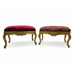Pair of Louis XV-design giltwood stools, each upholstered in red damask fabric with slight variations in patterns, the carved frames adorned with scrolling foliage and shell motifs, raised on cabriole supports