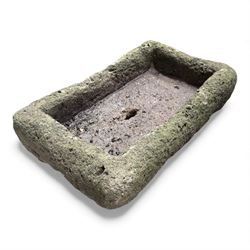 Collection of cast stone garden objects including mill stone, trough, planter, and faces
