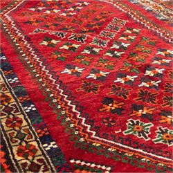 South West Persian Lori hand-knotted rug,  deep crimson field with a stepped lozenge medallion enclosing stylised floral motifs within multiple geometric borders of indigo, ivory, and green, with fringe ends 