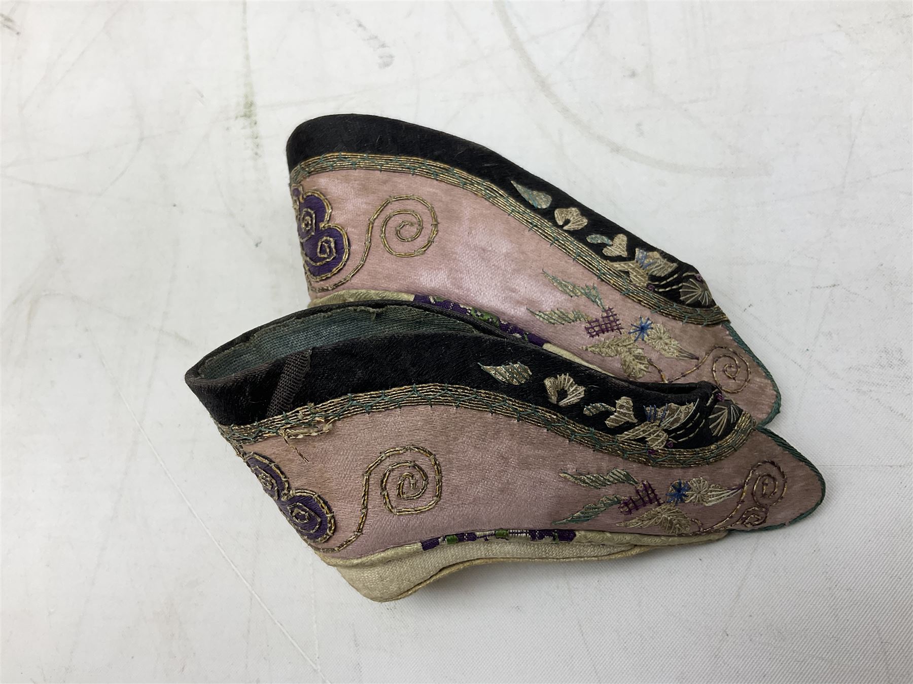 French silver plated wine taster of typical form, stamped, together with a silver plated napkin ring, and an 'Alpaca Silver' pill box with mother of pearl detailed cover, (3) together with Two pairs of late 19th/early 20th century Chinese Lotus shoes for binding feet, the first with purple silk heavily embroidered with ornate floral motifs, L10cm the second larger fuschia and black pair with thicker sole embroidered with flowers, L14cm