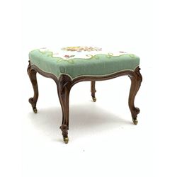 Victorian walnut drawing room stool, the top upholstered in floral needlework fabric, raised on scroll carved cabriole supports with floral decoration, terminating in brass castors 