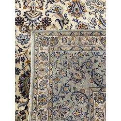 Persian Kashan ivory ground carpet, the field decorated profusely with scrolling foliate and stylised plant motifs, repeating guarded border