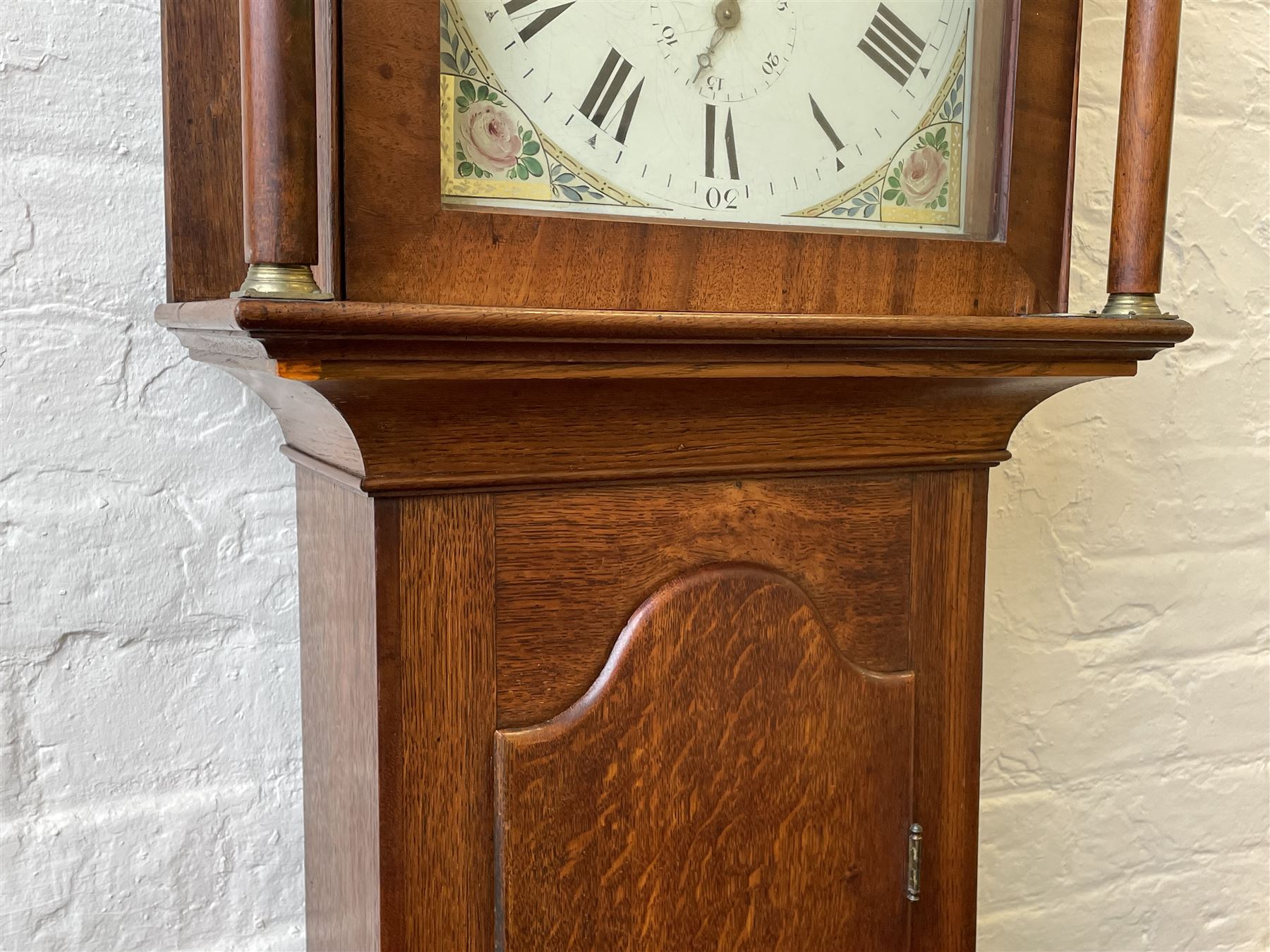 Thirty-hour oak cased longcase clock by  William Bancroft of Scarborough circa 1830, with a swan’s neck pediment, brass patera and three brass spire and ball finials, stepped break arch hood door flanked by plain pillars with brass capitals, trunk with a full length door and curved arch top, on a plain square plinth with bracket feet, painted break arch dial with roman numerals and quarter hour Arabic’s, date recorder (anti clockwise) and matching brass hands, arch painted with a rural scene depicting a ruined tower and cottage with depictions of flowers to the spandrels, dial pinned directly to a chain driven countwheel striking movement, striking the hours on a bell. With weight and pendulum. The Bancroft family were prodigious Scarborough clockmakers during the 18th and 19th century, William Bancroft is recorded as working in Newborough Street from 1820 onwards. 


