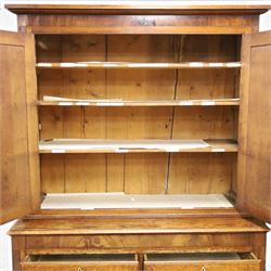 Georgian oak and mahogany housekeepers cupboard, the upper section with projecting cornice, crossbanded and inlaid frieze, above panelled doors with bone escutcheons, enclosing three fixed shelves, flanked by barley twist quarter pilasters, the lower section with further crossbanded and inlaid frieze, two short over two long graduating drawers with ebonised handles, raised on turned supports 