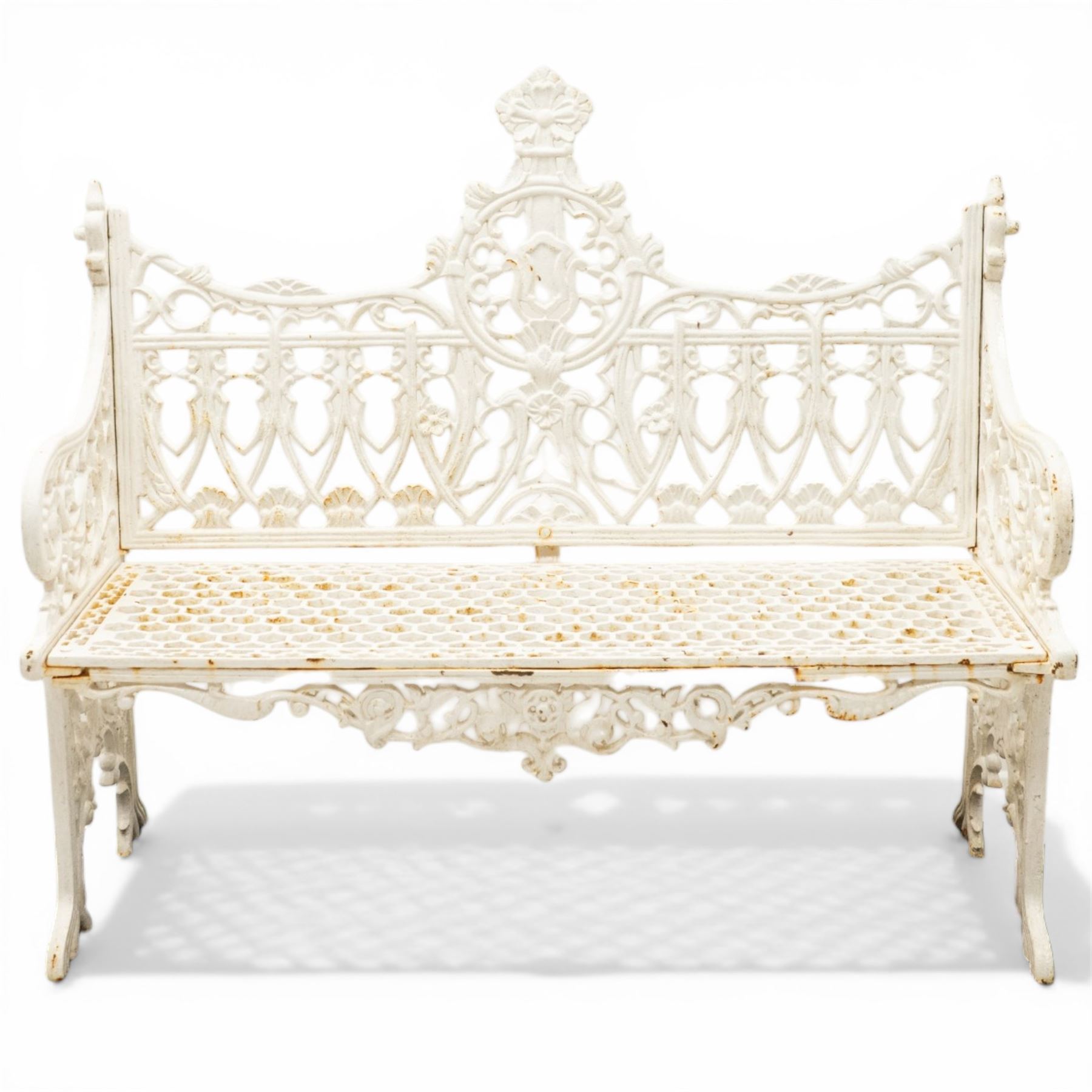 Victorian revival heavy cast iron garden bench, ornate back rest with scrolls, floral motifs and central crest, pierced lattice seat, curved arms and decorative legs, painted in antique white, in the Gothic Coalbrookdale style