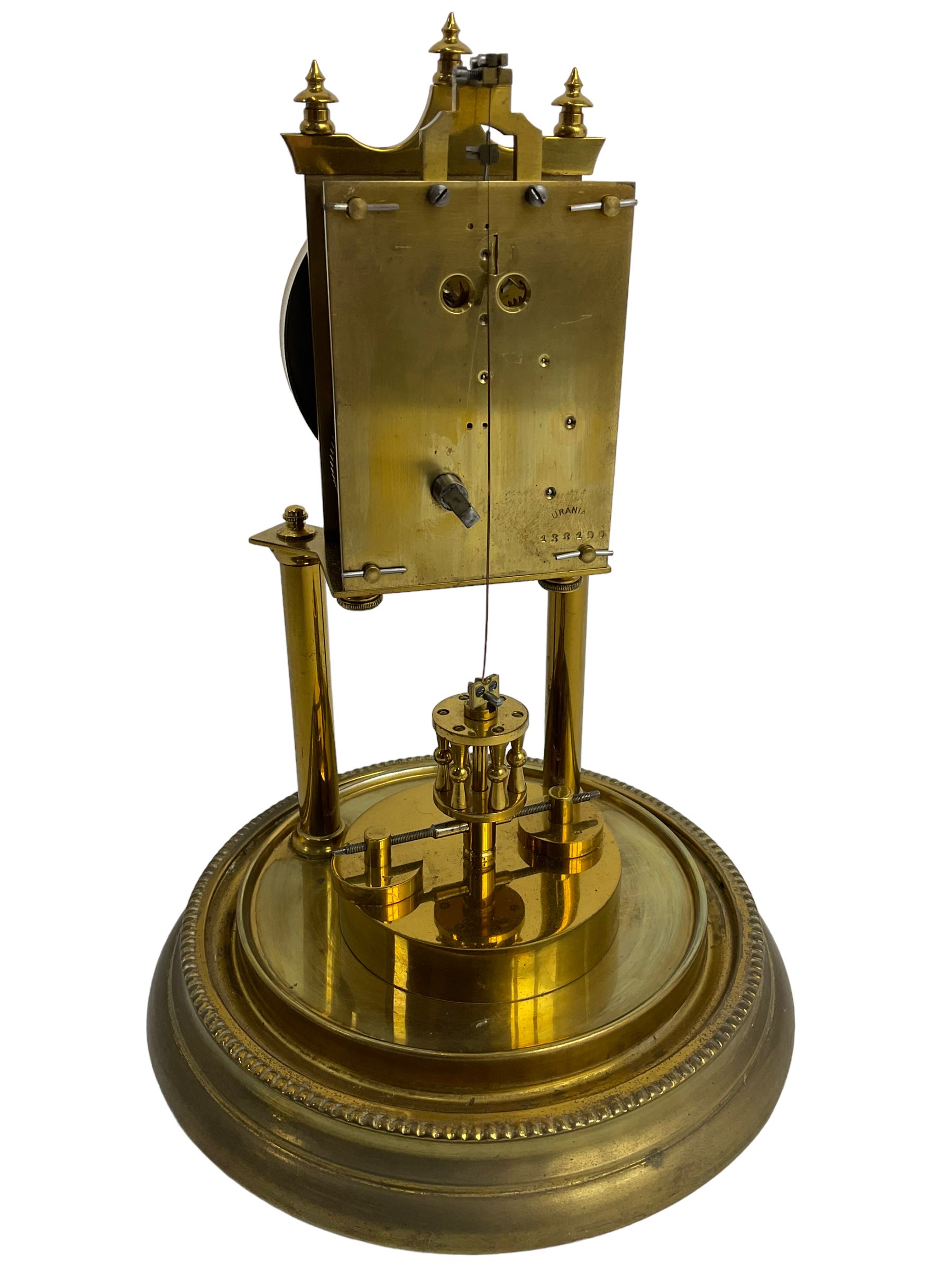 Gustav Becker - German Urania torsion clock with a glass dome, late 19th century 400-day movement with an enamel dial, arabic numerals and steel spade hands, movement supported by two brass pillars on a circular base, adjustable rotating pendulum with torsion suspension intact. With Key.