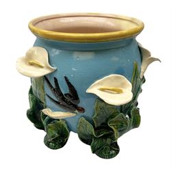 George Jones style majolica jardiniere of globular form, supported on four feet formed from modelled lily leaves growing up the side of the pot, with swallows flying amongst the white lily flowers, all set against a blue ground, with a pink interior, H27cm