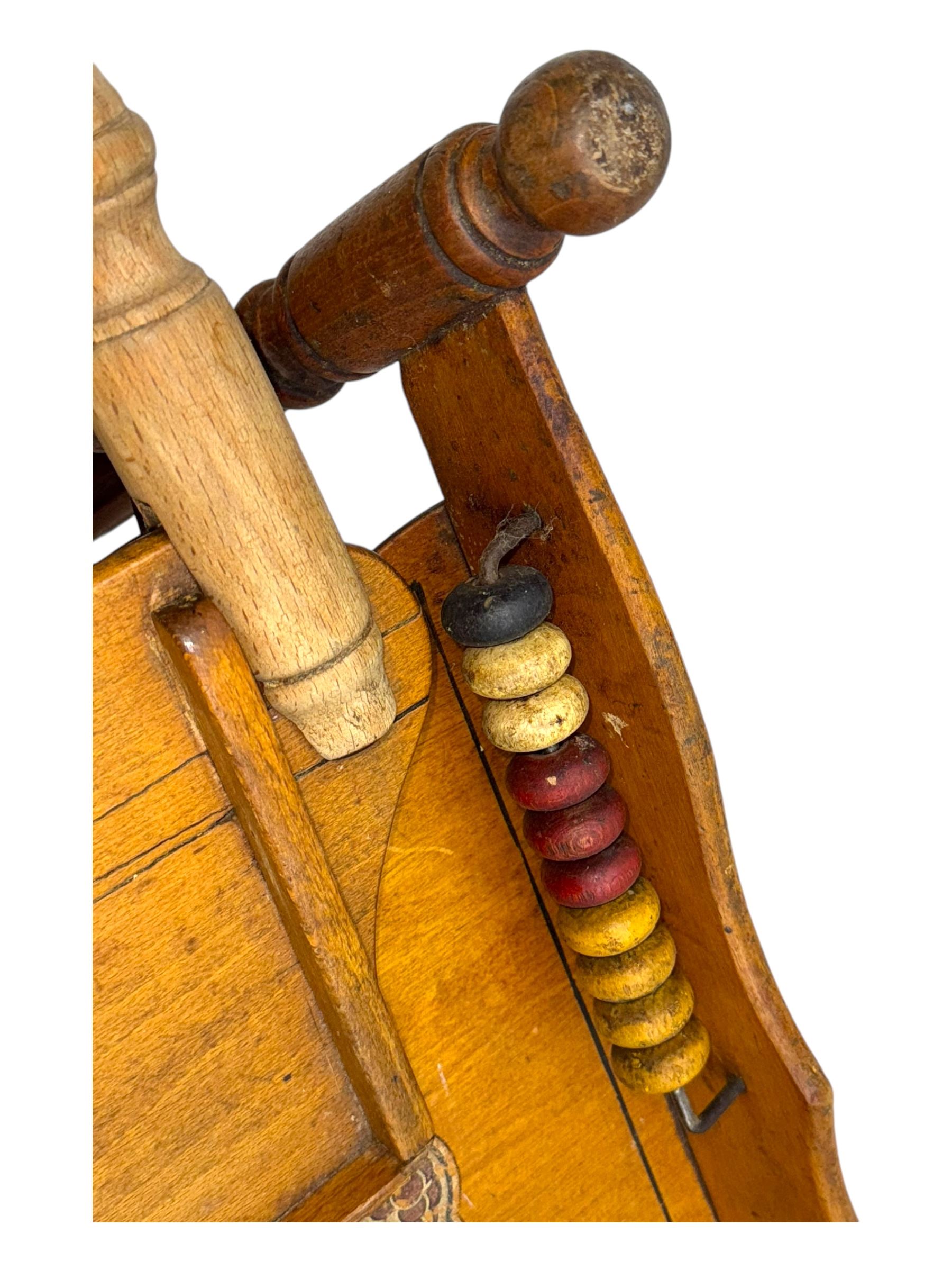 Late 19th century American oak child's metamorphic high chair and play table, carved spindle backrest with pierced splat, detachable tray with abacus and hand painted pastoral decoration, on turned supports with metal wheels