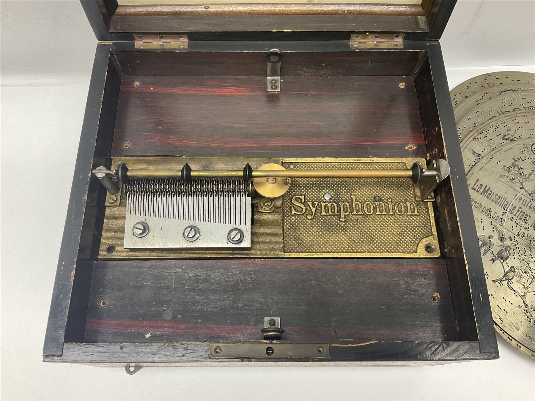Late 19th century Symphonion disc musical box for spares or repair, inlaid walnut case with front lever action, playing 25.5cm discs on a 10.5cm steel comb with forty-nine teeth, musical scene of cherubs under the lid, L33cm; together with twelve 25.5cm discs