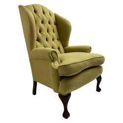 Queen Anne design hardwood framed wingback armchair, upholstered in green fabric with buttoned back, on acanthus carved ball and claw cabriole feet