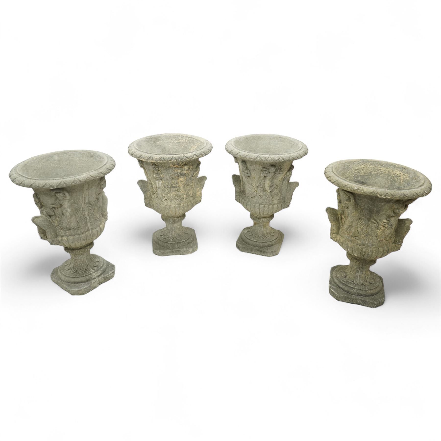 Late 20th century set of four composition stone campana urns, each with everted rim over acanthus and mask relief decoration, tapering to a fluted socle on square plinth base