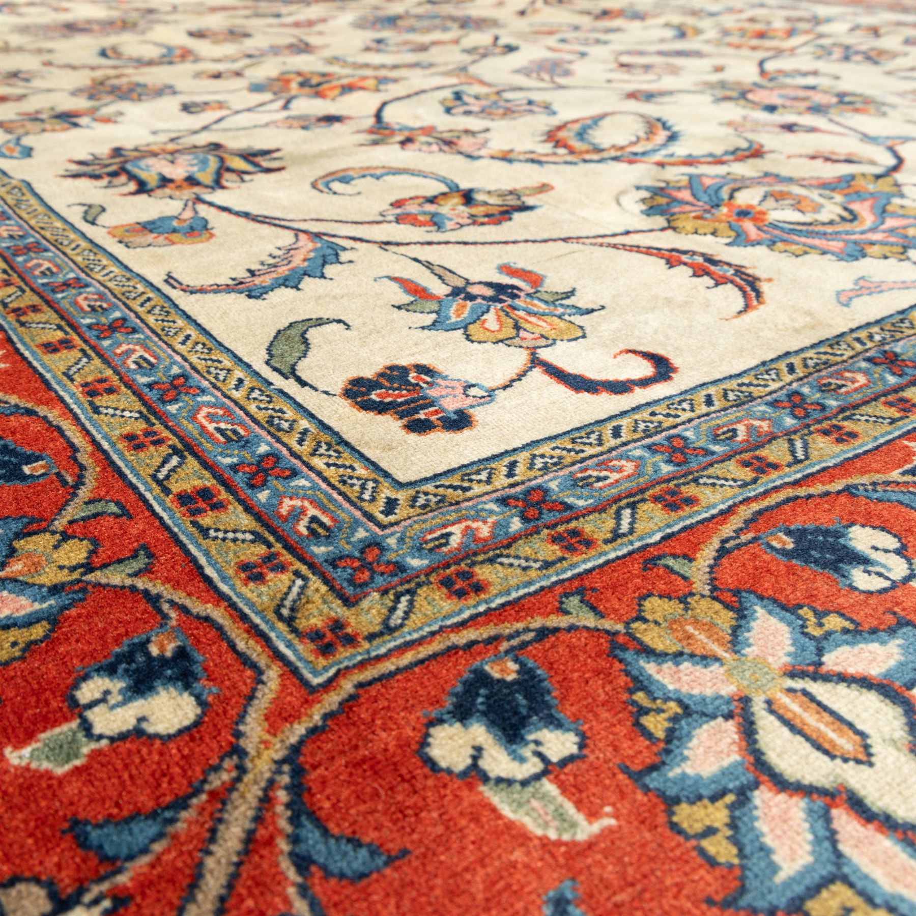 Persian Sarough carpet, ivory field with symmetrical arrangement of scrolling vines, palmettes and floral sprays in red, blue and green, enclosed by a broad red main border with repeating floral motifs, originating from the Arak region of Iran
