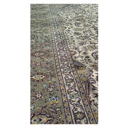 Kashan Persian rug, hand knotted, ivory ground rug, the rosette medallion decorated with projecting palmettes, on a field of swirling leafy branches and decorated with further palmettes, the scrolling border with repeating stylised plant motifs, within floral pattern guard stripes