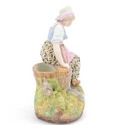 Late 19th/early 20th century Continental bisque figures, the larger modelled as a pensive female figure sitting upon a well, upon an oval naturalistically modelled base, H39cm, the smaller modelled as a hunts woman holding a bird aloft, with hound by her side, upon a socle base, H35cm