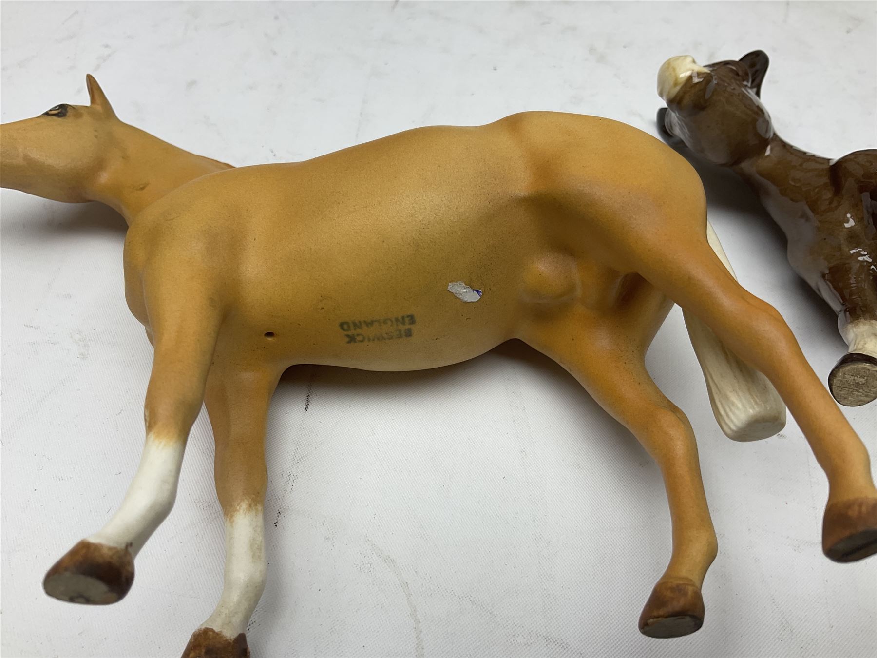 Four Beswick horse figures, comprising Quarter Horse, two Shires no 818 and matt palomino, together with Beswick donkey and Royal Doulton horse on a wooden plinth  