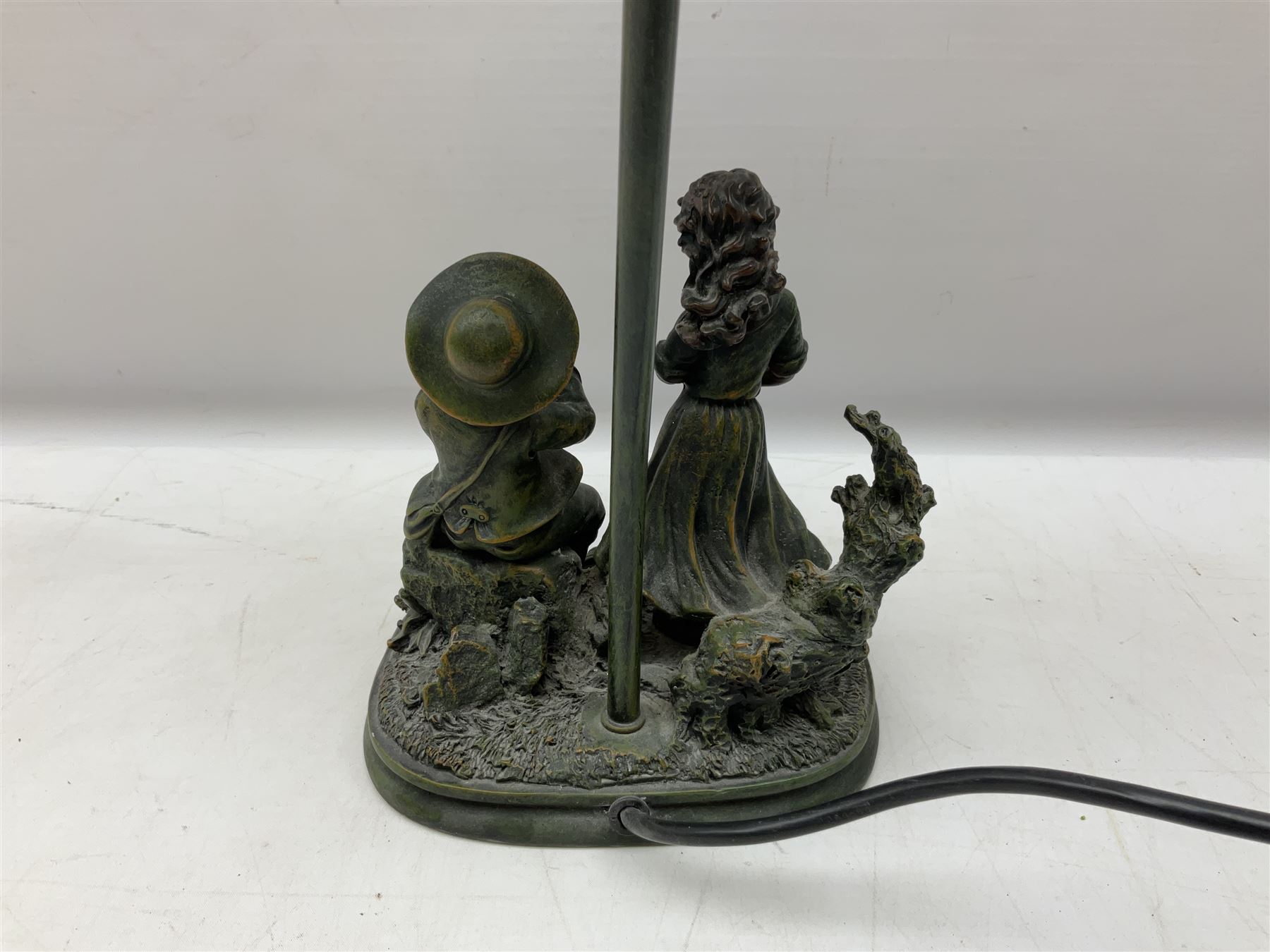 Art Deco style Widdop Bingham & Co desk lamp, modelled as boy and girl playing instruments, on naturalistic base with yellow and green frilled glass shade, with sticker label beneath, H42cm, and A Belcari figural table lamp, modelled as a young gent leaning upon brick wall, on turned wood base, signed, H70cm incl shade, together with bronzed figural table lamp of a lady with parasol upon ornate circular plinth base, two ceramic table lamps and another lamp (6)