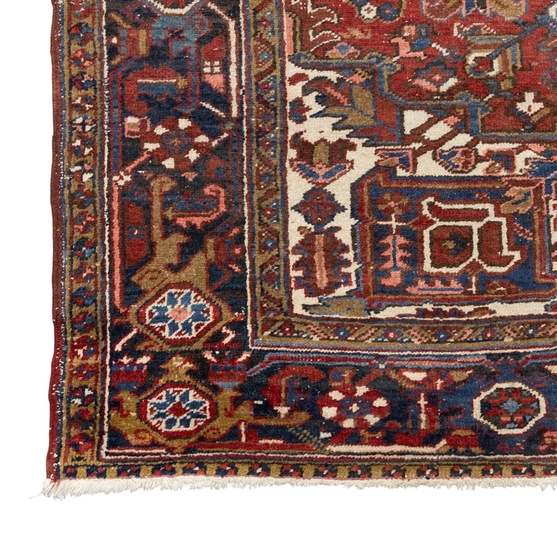 Persian Heriz carpet, red ground with large central geometric medallion, angular flowering branches and stylised foliate decoration, within a broad dark blue floral border and narrow guard stripes