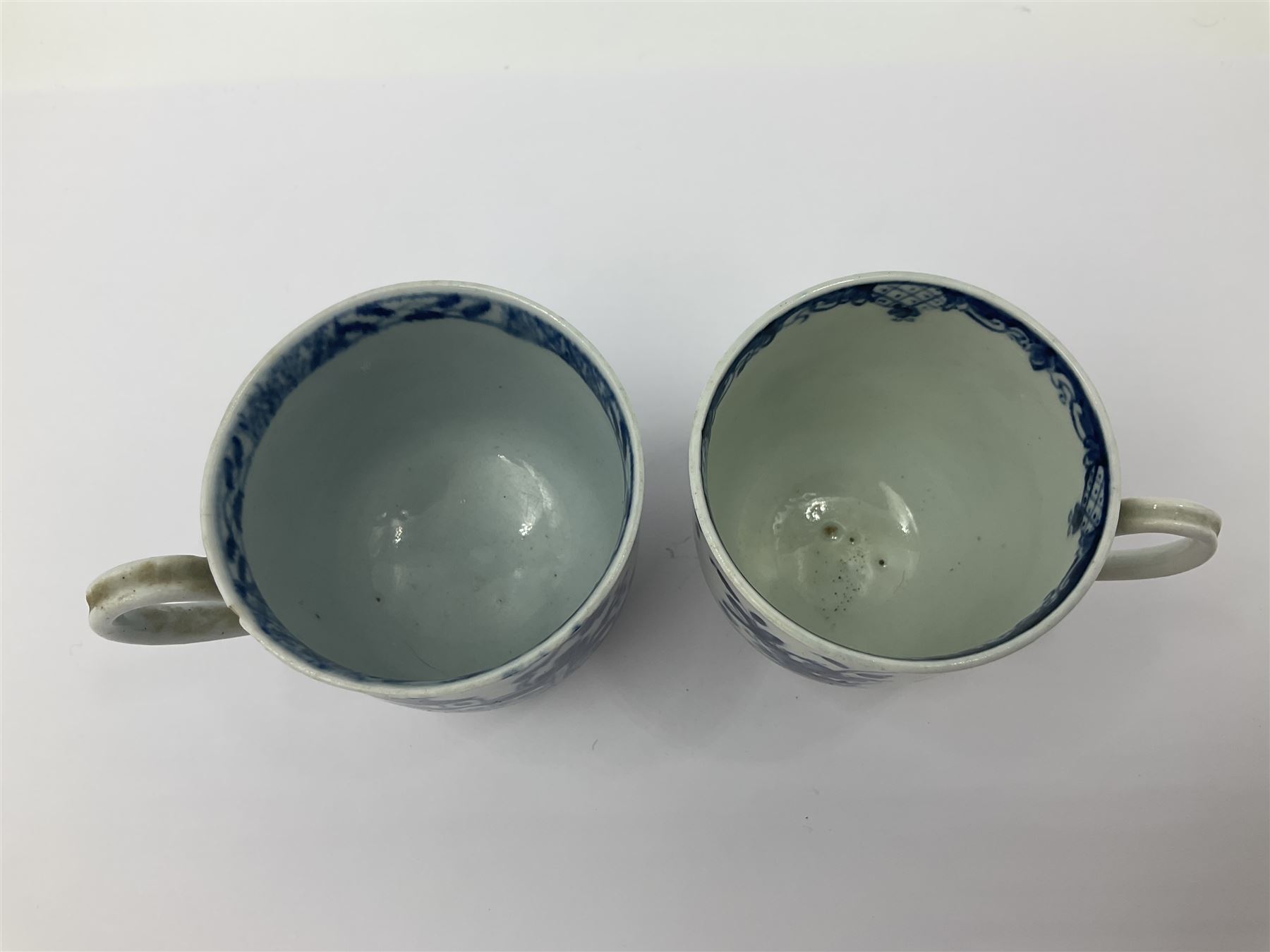 Two 18th century Worcester porcelain coffee cups, the first example decorated in the Plantation pattern, circa 1754, the second decorated in the Mansfield pattern, circa 1760, with workman's mark beneath, each approximately H5.5cm
