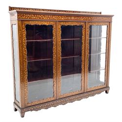 Early 20th century mahogany and Dutch style marquetry display cabinet, inlaid throughout with trailing foliage, flower heads and masks, three glazed doors with shaped scalloped edge enclosing three adjustable shelves, on square tapered feet