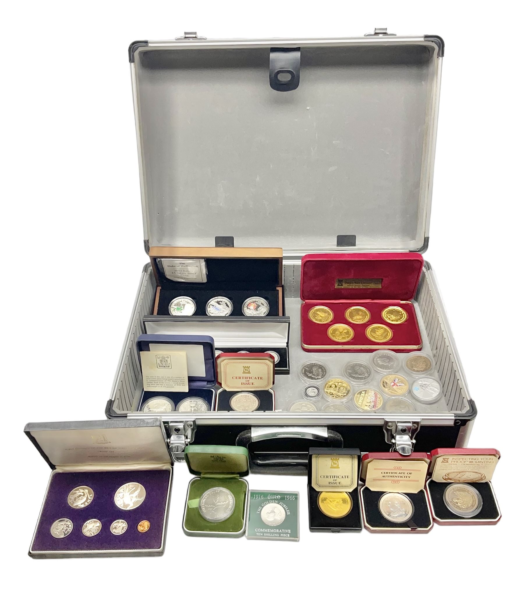 The Royal Mint United Kingdom 1977 silver proof two coin set, Queen Elizabeth II 2002 silver proof three coin set, comprising Bailiwick of Jersey, Bailiwick of Guernsey, and Alderney five pound coins, 'First Coinage of the British Virgin Islands' proof set, 1997 1/10 ounce fine silver Britannia, two King George V 1935 'Rocking Horse' crowns, various Isle of Man commemorative crowns, etc., house in a hard shell carry case