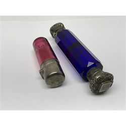 Late Victorian silver mounted ruby glass cylindrical scent bottle, with interior glass stopper, Birmingham 1900, makers mark worn, H8cm, together with a Victorian double ended cut blue glass perfume bottle mounted with white metal screw and flip caps decorated with foliate repousse detailing, H13.5cm