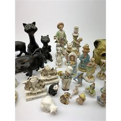 A collection of various ceramic figurines, to include pair of small 19th century Staffordshire cats, Royal Doulton cat, Coalport cat, pair of 19th century pug dogs, two fairings inscribed Good Templars, two Bonzo dog peppers, a number of pin cushion dolls, various 20th century and later black pottery cats, Victorian bisque figures, etc. 