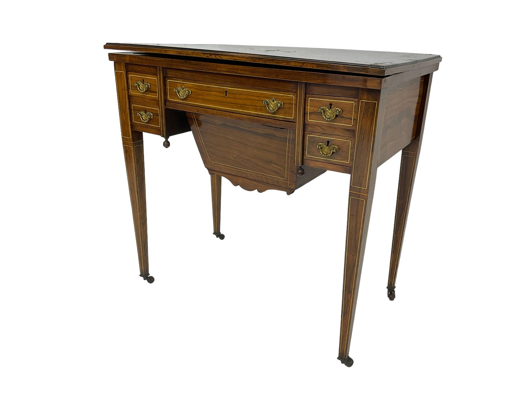 Edwardian inlaid mahogany games or work table, rectangular fold-over top inlaid with stylised dragon ivorine decoration and stringing, fitted with one long flanked by four small drawers over sewing compartment drawer, raised on square tapering supports with castors