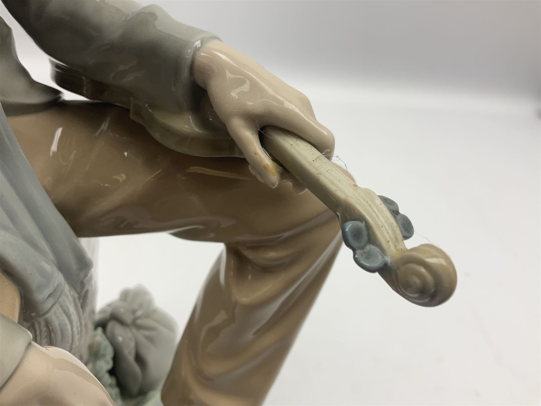 Lladro figure, Violinist, modelled as a man seated upon a  mile stone holding a violin, sculpted by Salvador Furió, no 4887,  year issued 1984, year retired 1981, H35cm