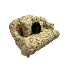 Victorian style two seat sofa, upholstered in beige ground floral floral pattern fabric, with scatter cushions, turned feet with brass castors