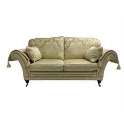Steed Upholstery - two seat traditional shaped sofa, upholstered in cream fabric with scrolling foliate pattern, on turned front feet with brass castors, with side cushions and arm covers