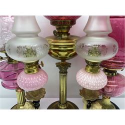 Victorian cast brass oil lamp, with fluted pink glass shade, together with two smaller brass oil lamps with pink shades and reservoirs and a pair of oil lamps, the bases modelled as putti, with pink glass reservoir  and frosted shades, tallest H70cm